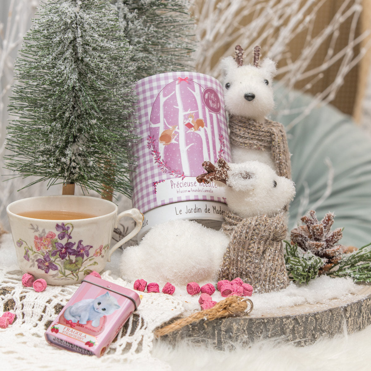 Boîte de thé Infusion Précieuse Récolte à carreaux roses, décorée de motifs d’hiver, avec deux peluches d’ours blancs.