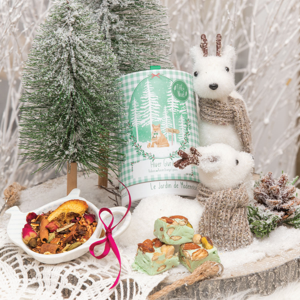 Boîte verte de thé Rooïbos Hiver Givré avec illustrations hivernales, entourée de décorations de Noël et d’infusion.